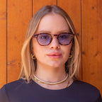 Aqua Tortoise sunglasses with gradient blue lenses worn by a woman against a wooden backdrop.