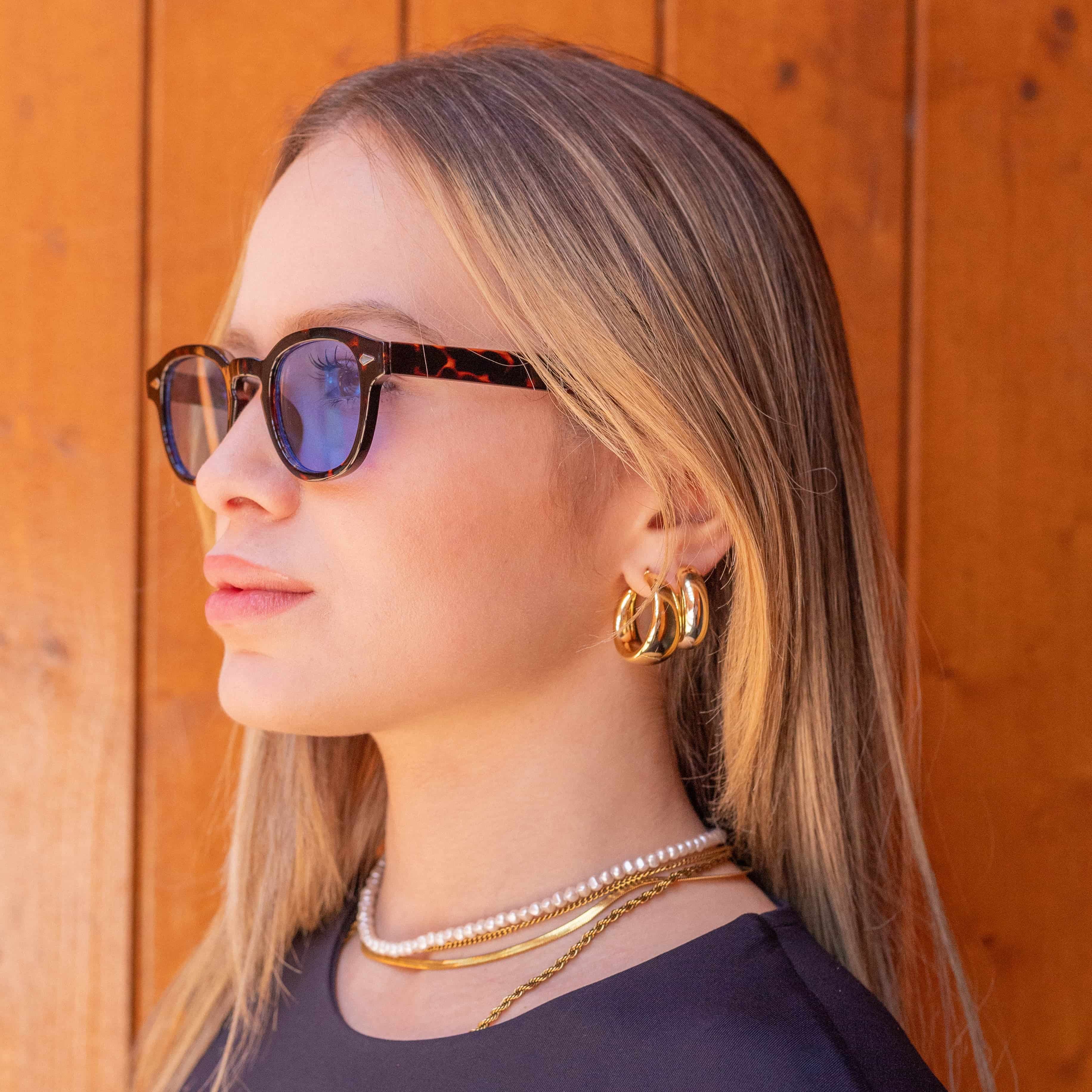 Model wearing Deep Tortoise sunglasses with gradient blue lenses, showcasing a stylish look.