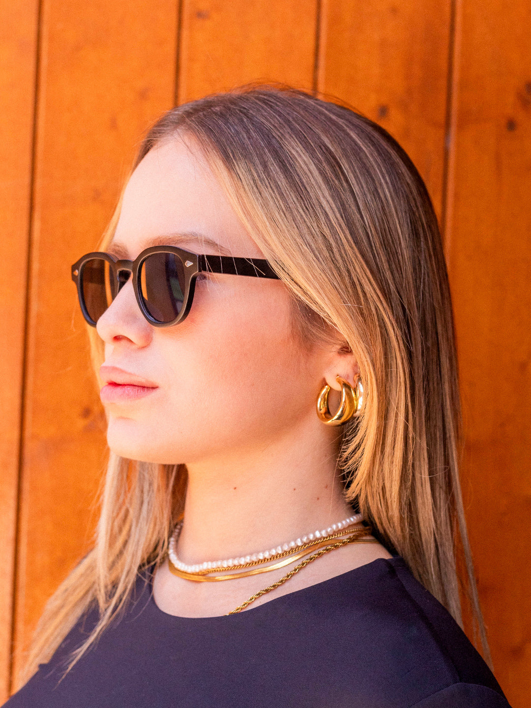 Full-length lifestyle photo featuring a person wearing harbor black black sunglasses by Alga.